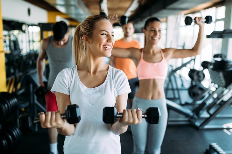 Mulheres sorrindo durante exercício na academia.