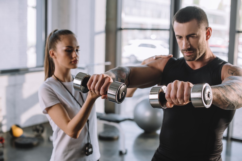 Personal trainer com aluno no treino de musculação