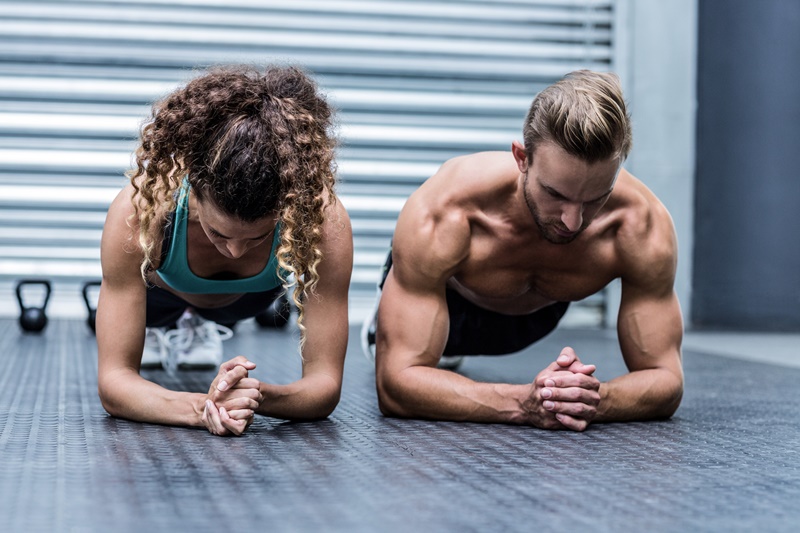 Vista frontal de um casal musculoso fazendo exercícios de prancha