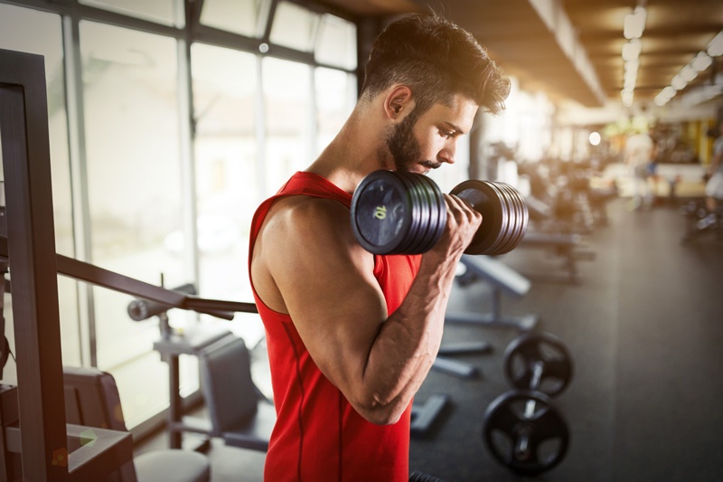 homem fazendo musculação com halter na academia