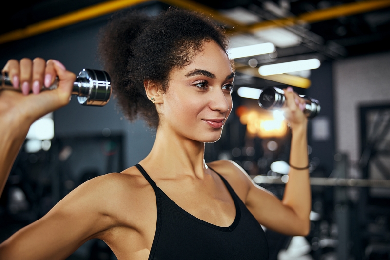 Mulher positiva e encantada, mantendo um sorriso no rosto enquanto trabalha em seu corpo perfeito
