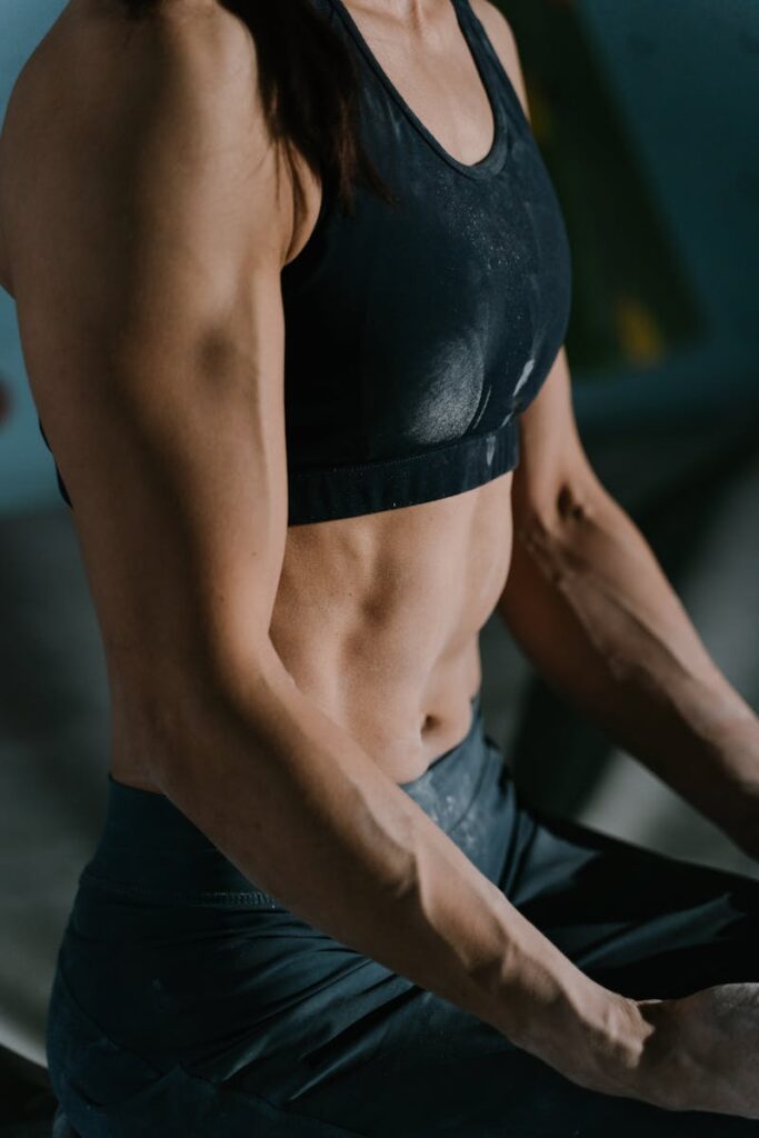 Close-up de uma mulher musculosa descansando durante uma sessão de treino intenso em ambientes fechados.